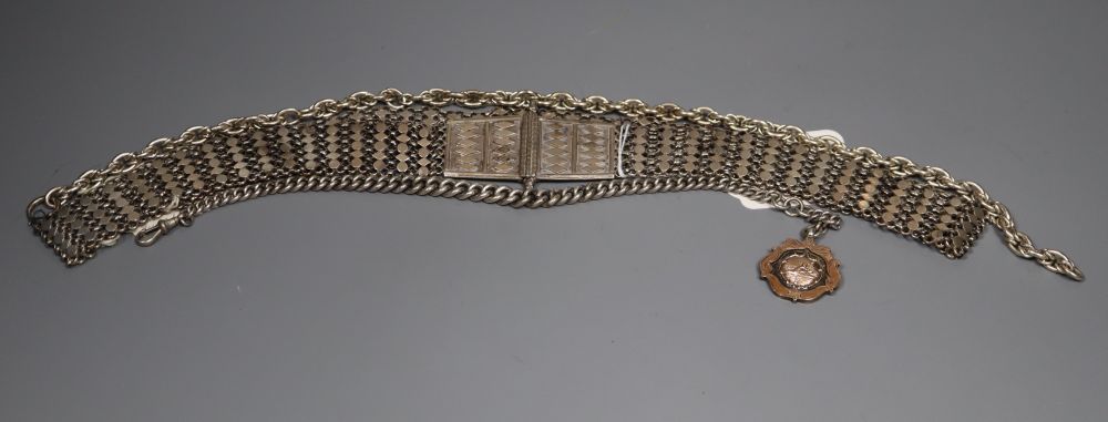 An Indian white metal belt and two alberts including silver and a silver and yellow metal medallion.